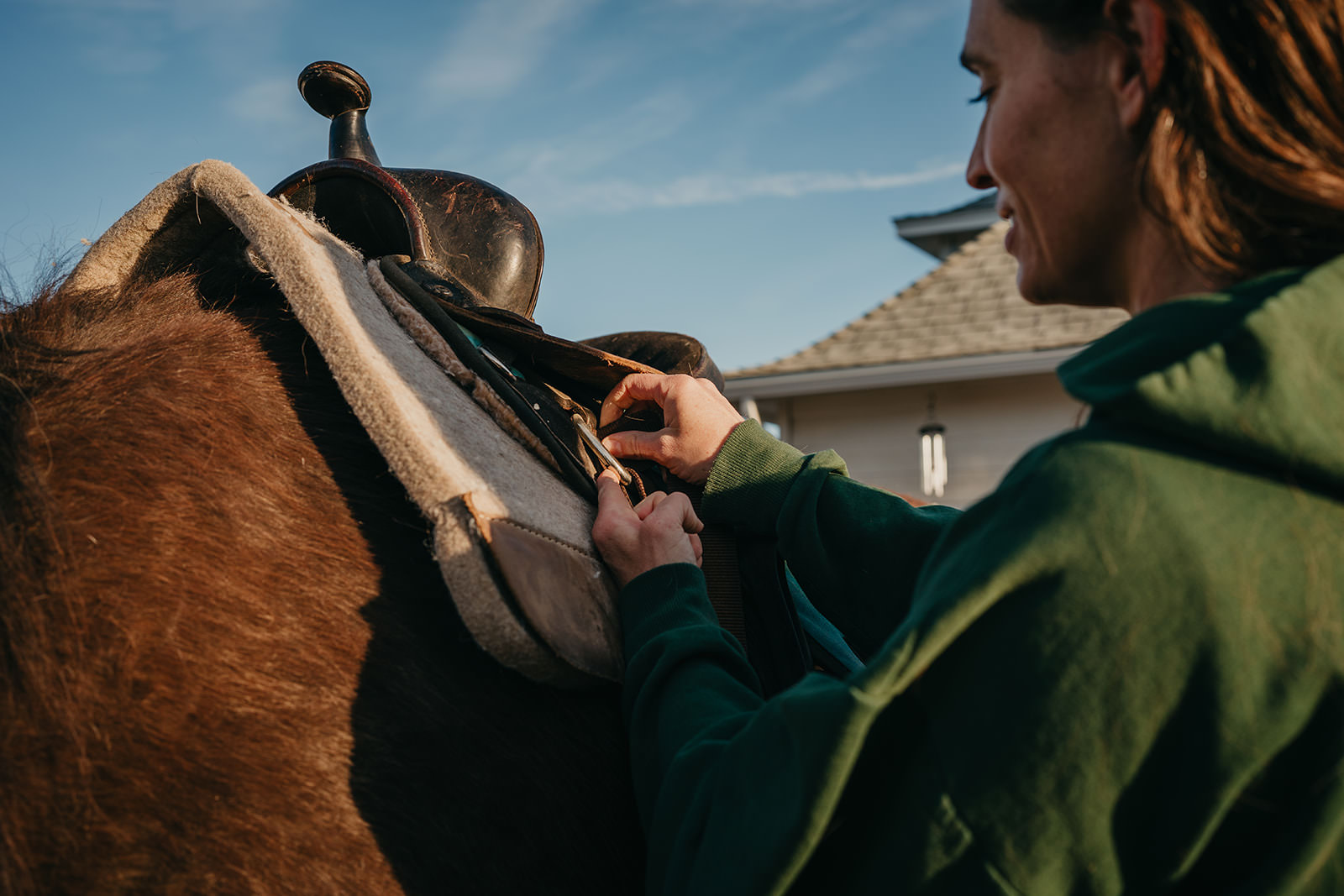 equine therapy branding photos of woman saddling horse.