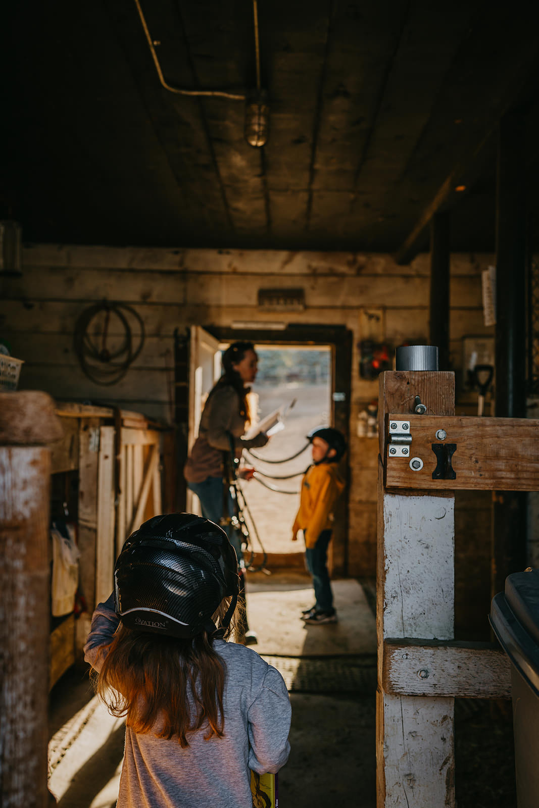 equine therapy branding photos of woman with kids in barn.