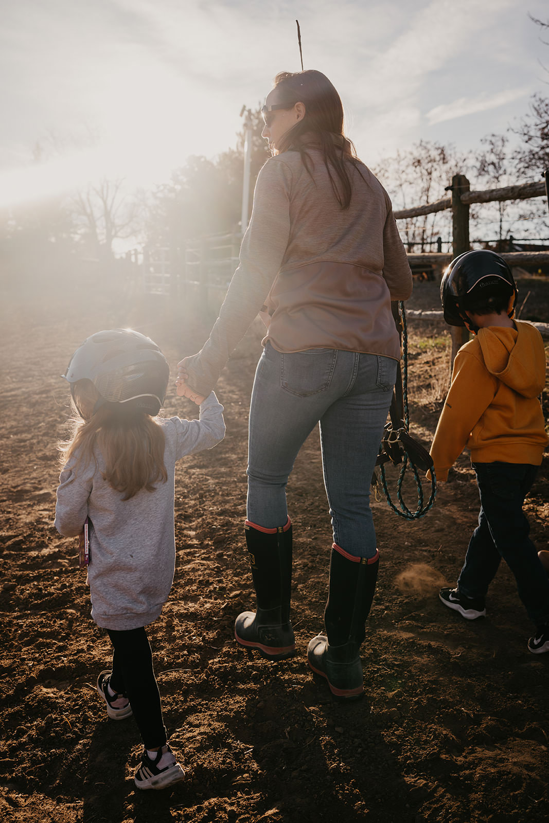 equine therapy branding photos of woman walking with kids in stable.