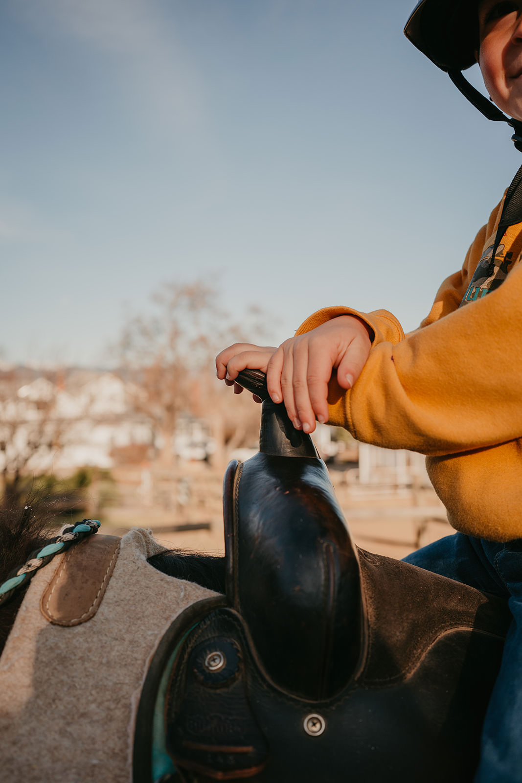 equine therapy branding photos of child's hands on saddle horn.