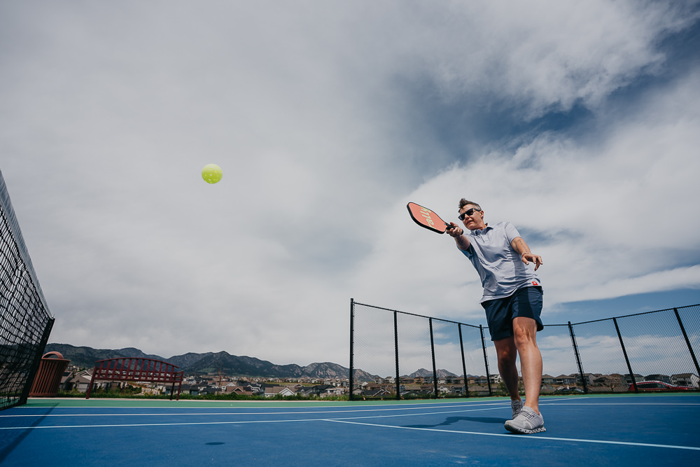 Brand photo of queer woman playing pickleball.