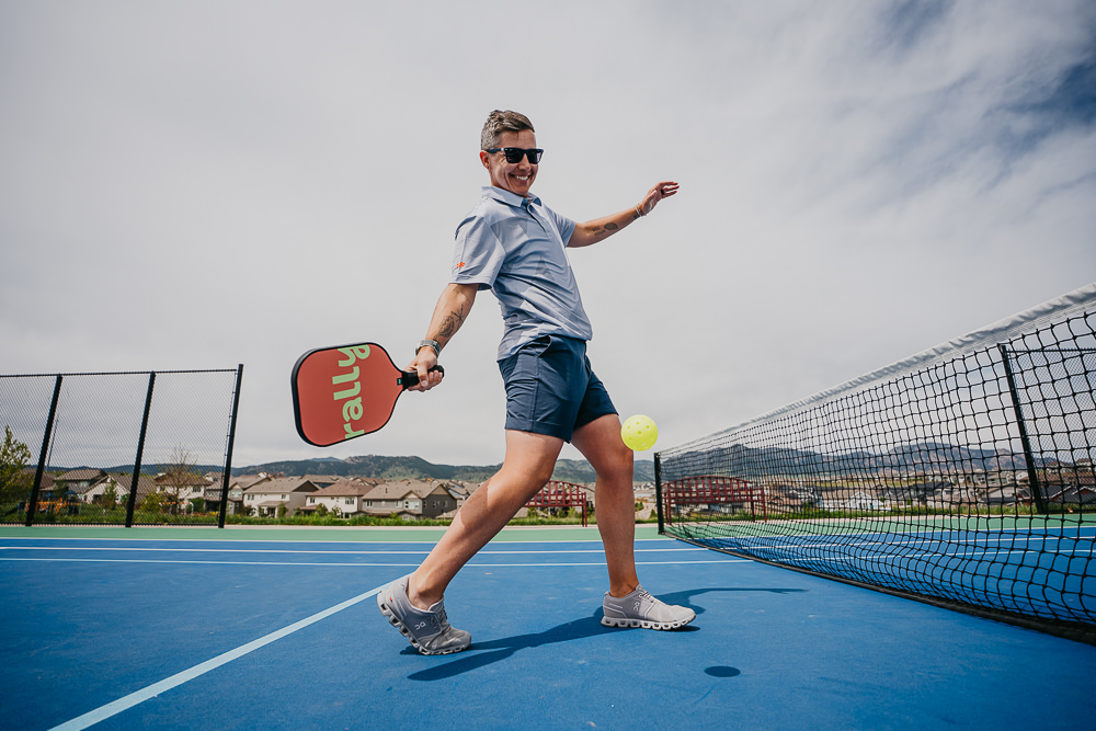 Brand photo of queer woman playing pickleball.
