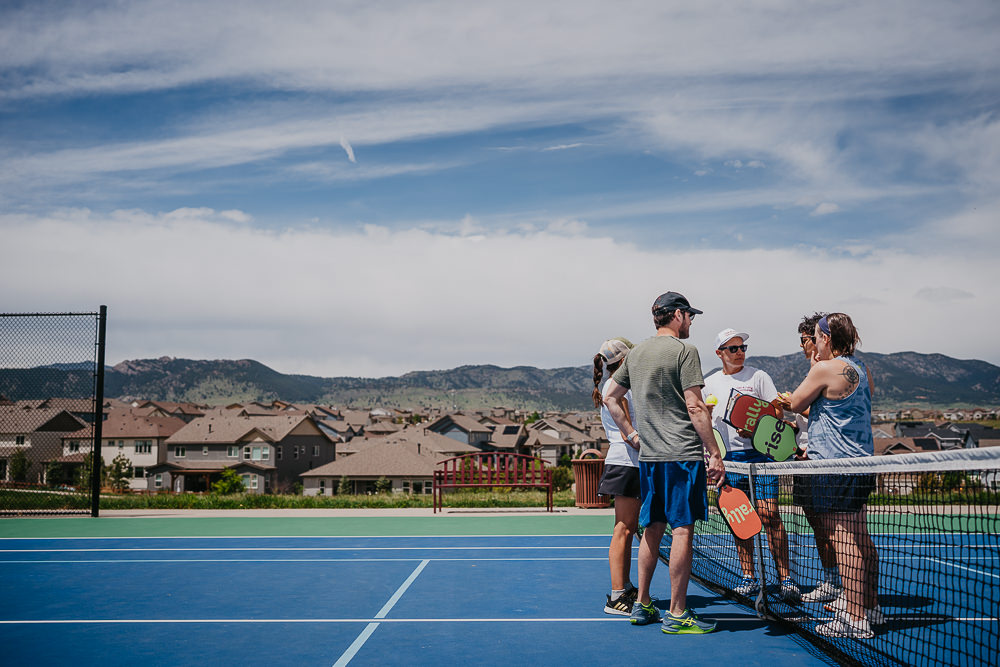 Brand photo of group meeting on pickleball court.