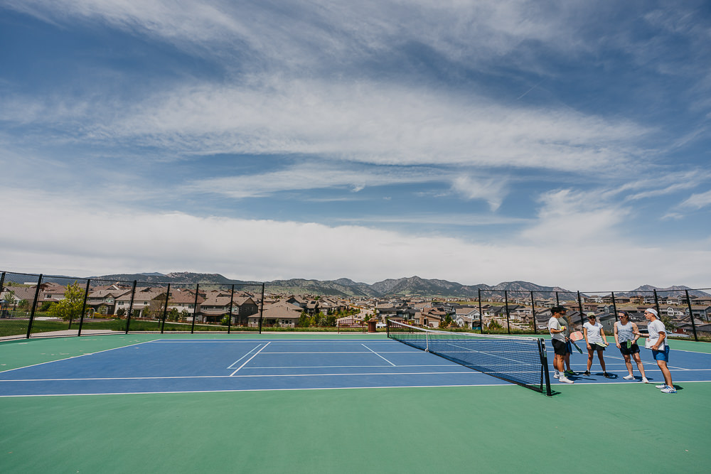 Brand photo of group meeting on pickleball court with mountains in the background.