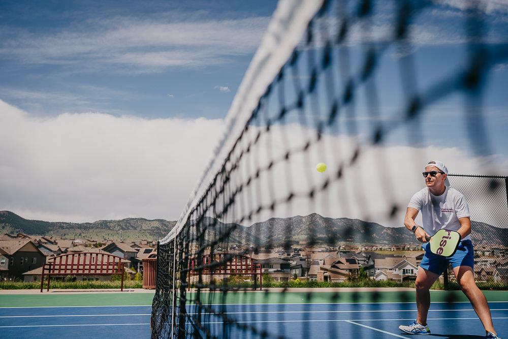 Brand photo coach playing on pickleball court with mountains in the background.